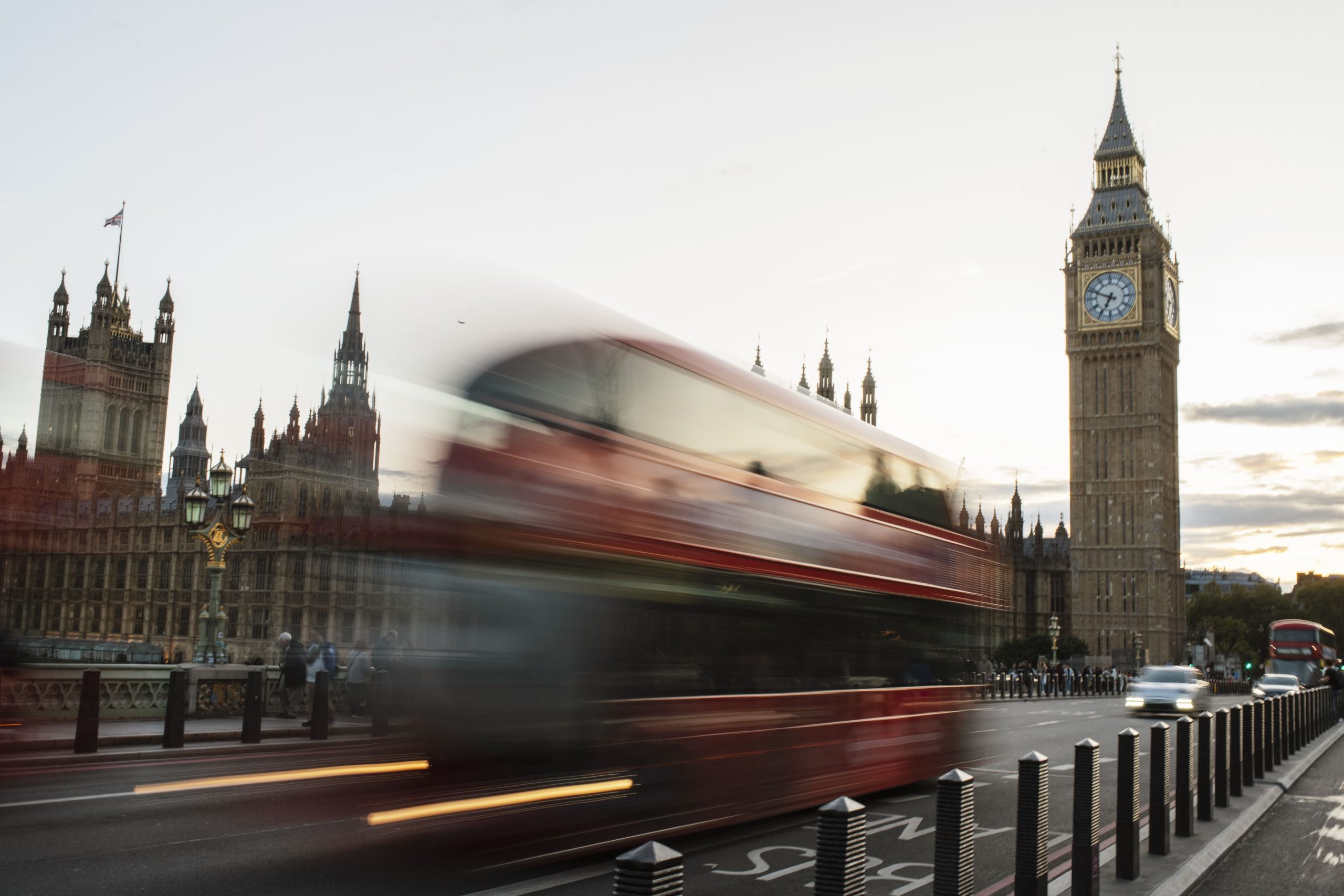 Image of blurred red bus driving past Big Ben in a busy London street